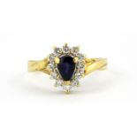 An 18ct yellow gold cluster ring set with a pear cut sapphire surrounded by diamonds, (L).