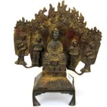 A Tibaten bronze figure flanked by monks with a flamed tankgha style surround, H. 23cm.