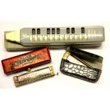 A cased Hohner melodica and two harmonicas.