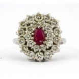 A white metal (tested minimum 18ct gold) cluster ring set with an oval cut ruby and brilliant cut