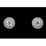 A pair of 18ct white gold stud earrings set with a centre brilliant cut diamond surrounded by