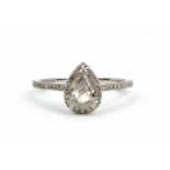 An 18ct white gold solitaire ring set with a pear cut diamond surrounded by brilliant cut