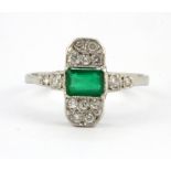 A white metal (tested platinum) emerald and diamond set ring, (R).