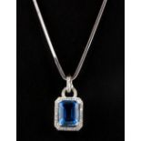 An 18ct white gold (stamped 750) pendant set with an emerald cut blue topaz surrounded by