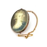 A yellow metal mounted hand painted portrait brooch, L. 3cm.