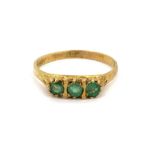 A 9ct yellow gold ring set with three round cut emeralds, (N).