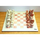 A carved stone chess set, king H. 13cm.