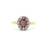 A yellow metal (tested 18ct gold) cluster ring set with an oval cut ruby and brilliant cut diamonds,