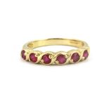 A 9ct yellow gold half eternity ring set with rubies, (N).