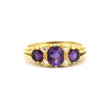 An 18ct yellow gold ring set with oval cut amethysts and rose cut diamonds, (O).