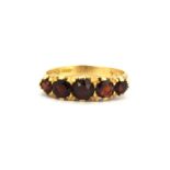 An 18ct yellow gold garnet set ring, (M).