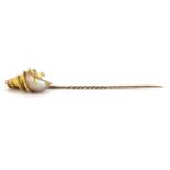 A yellow metal (tested 18ct gold and 9ct gold pin) shell mounted stick pin, L. 8.5cm.