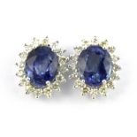 A pair of 18ct white gold (stamped 750) cluster earrings set with an oval cut sapphire surrounded by