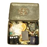 A tin of mixed costume jewellery.