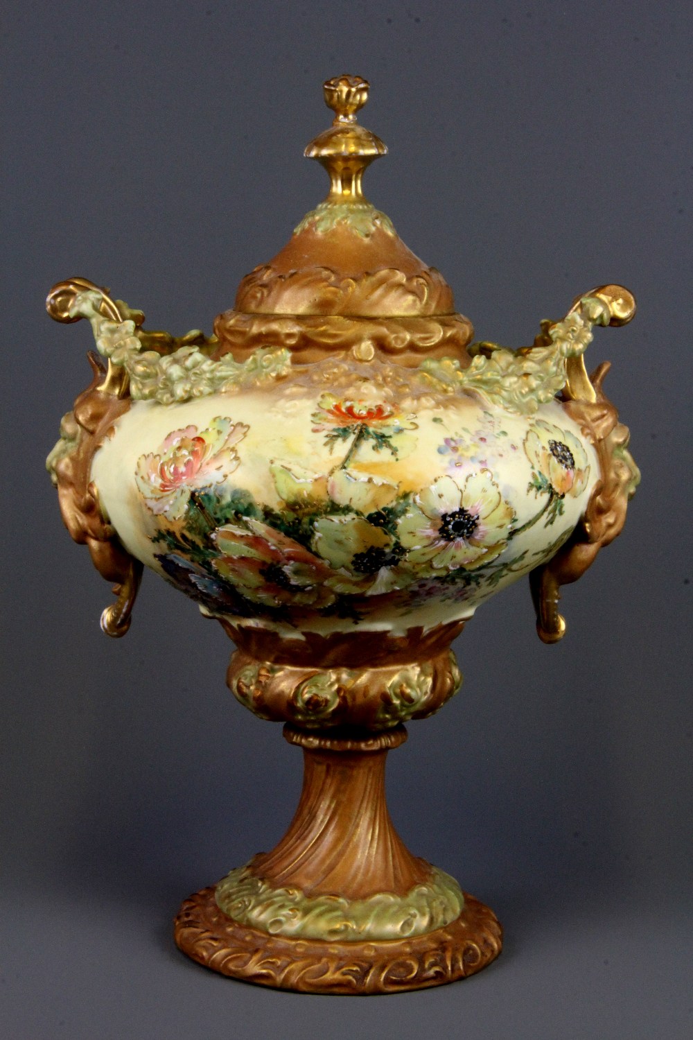 A 19th Century hand painted Continental porcelain urn and lid with green man handles, H. 30cm.