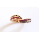 An 18ct yellow gold crossover ring set with baguette cut diamonds and rubies, (L.5).