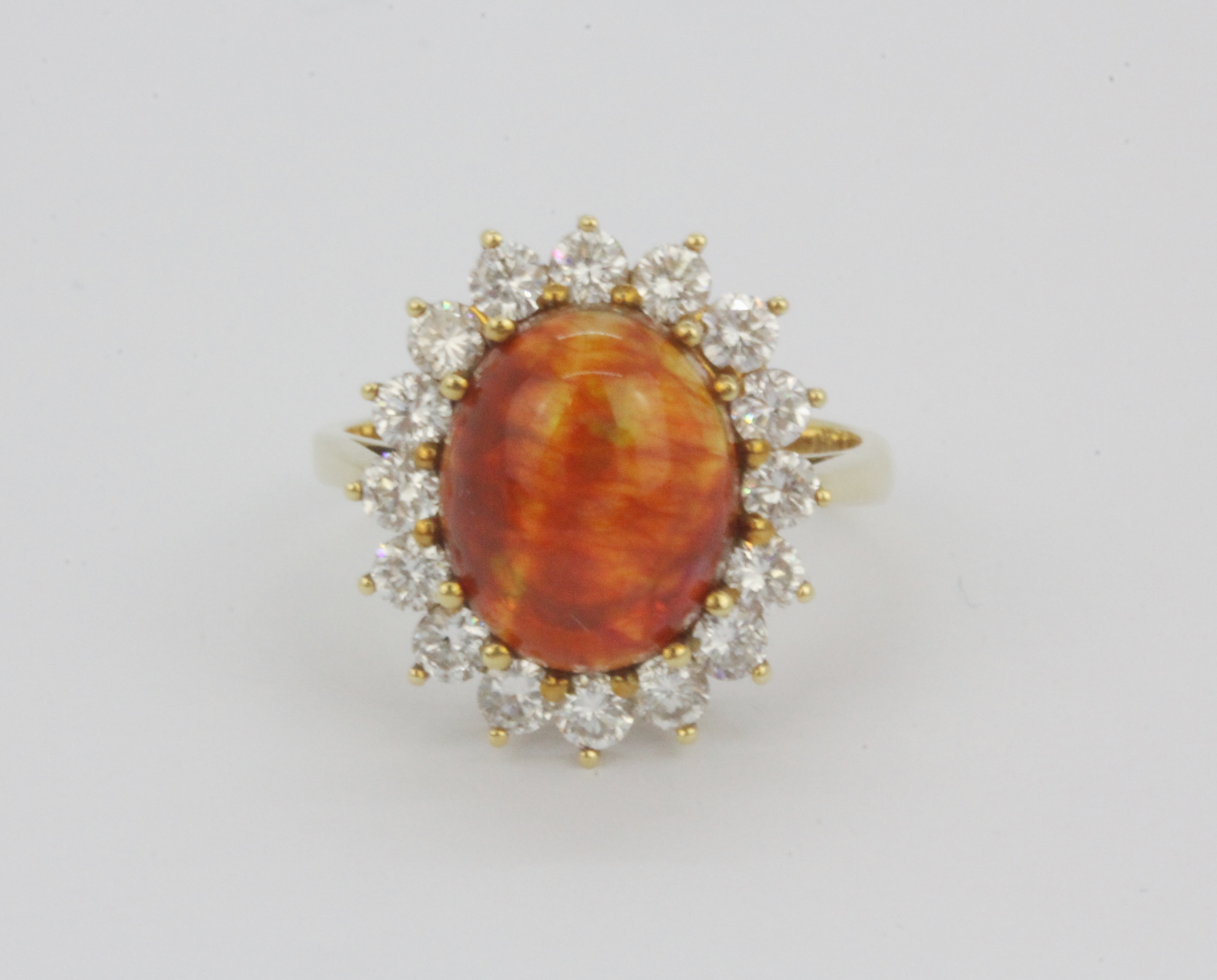 An 18ct yellow gold cluster ring set with a large cabochon cut opal, approx. 1ct diamonds