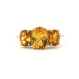 A 9ct yellow gold ring set with three oval cut graduated citrines, (J).