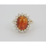 An 18ct yellow gold cluster ring set with a large cabochon cut opal, approx. 1ct diamonds