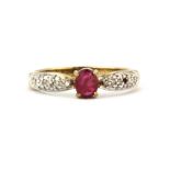A 9ct yellow gold ring set with an oval cut ruby and diamond set shoulders, (one stone missing), (
