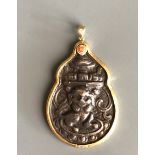 A yellow metal mounted Tibetan bronze stupa lion amulet inset with a small coral bead. H. 7cms.