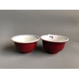 A pair of hand painted and sang de boeuf glazed porcelain tea bowls, D. 9.5cm H. 5.5cm. Condition