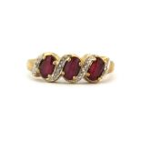 A 9ct yellow gold ring set with three oval cut rubies and diamonds, (L.5).