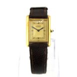A gilt Must de Cartier wrist watch with a leather strap. Understood to be in good working