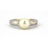 An 18ct white gold pearl set ring with diamond set shoulders, (K).