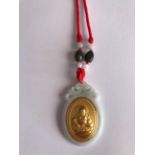A modern carved jade amulet inset with a yellow metal, tested high carat gold, image of Putai, the