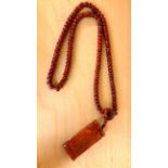 A strand of Tibetan carved yak bone prayer beads with carved yak bone mantra amulet, folded L. 59cm.