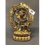 A Tibetan gilt bronze guardian deity figure fighting off an underworld figure wearing a skull crown.