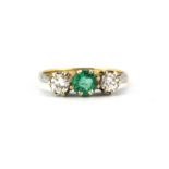 An 18ct yellow and white gold ring set with a round cut emerald flanked by brilliant cut diamonds,