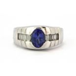 A heavy gentleman's 14ct white gold (stamped 14k) ring set with an oval cut tanzanite and baguette
