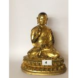 A Tibetan gilt bronze figure of a Lama seated in lotus position on a lotus pedestal and holding a