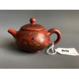 A 20thC Yixing terracotta teapot with black and gilt erotic decoration. H. 7cms. Condition good.