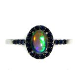 A 925 silver cluster ring set with a cabochon cut opal and sapphires, (P).