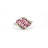 A 9ct white gold ring set with oval cut pink sapphires and diamonds, (M.5).