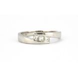 An 18ct white gold (stamped 18k) ring set with three princess cut diamonds, (N).