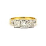 An 18ct yellow and white gold ring set with three princess cut diamonds and diamond set shoulders,