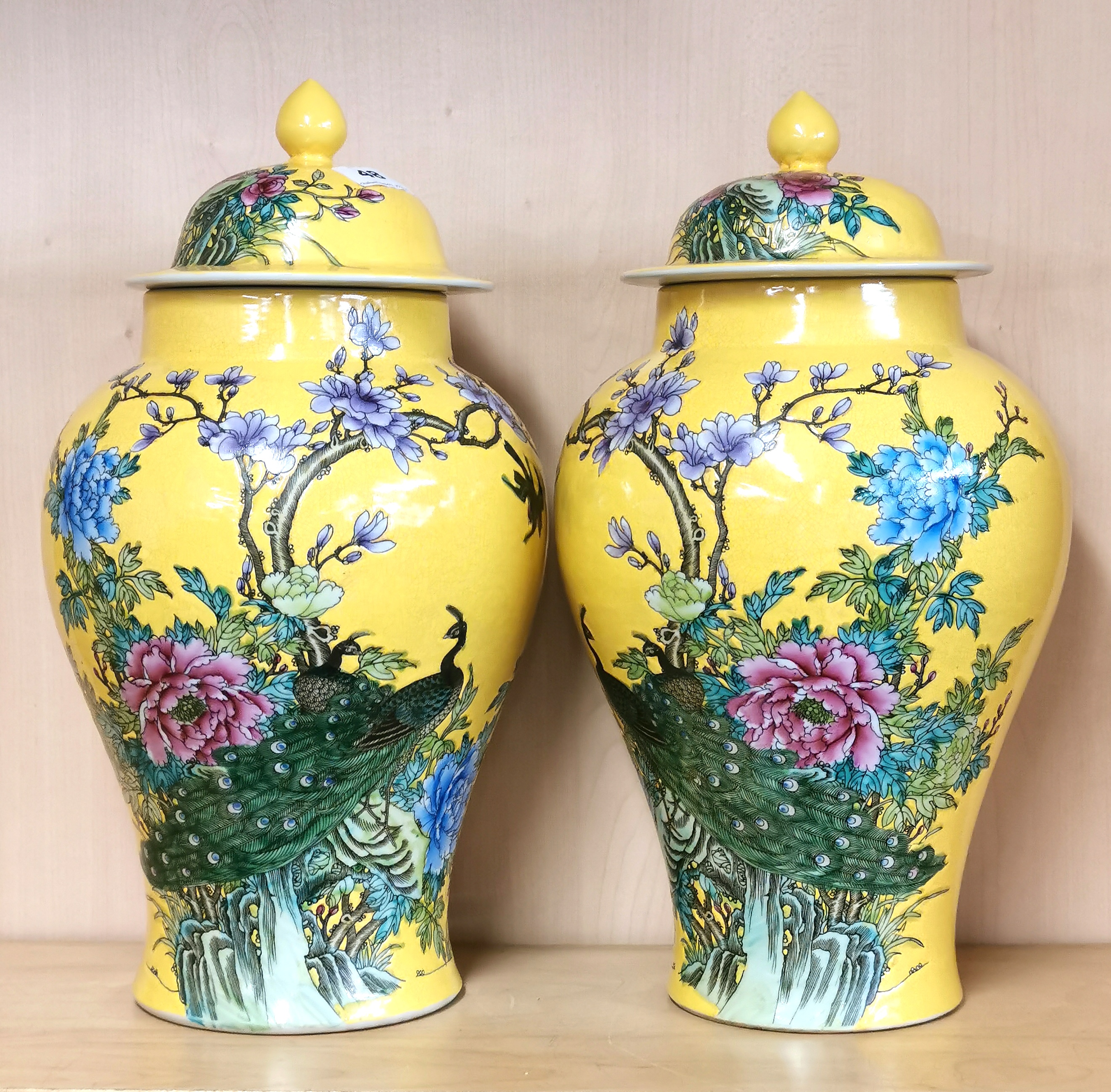 A pair of Chinese hand painted Imperial yellow porcelain jars and lids decorated with peacocks, H.