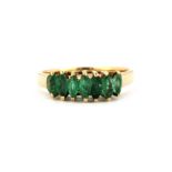 A yellow metal (tested 9ct gold) ring set with marquise cut emeralds, (Q.5).