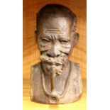 A charming African carved hardwood bust of a man smoking a pipe, H. 24cm.