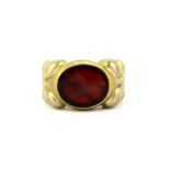 A gentleman's yellow metal signet ring set with a carved red stone, (L).