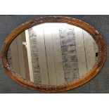 A large 1920's carved walnut oval mirror, size 100cm.