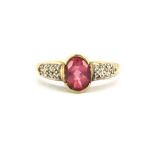 A 9ct yellow gold ring set with an oval cut pink tourmaline and diamond set shoulders, (P).