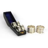 A cased set of four hallmarked silver napkin rings and two further napkin rings.