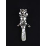 A 925 silver and mother of pearl teddy bear baby's rattle with glass eyes, L. 9cm.