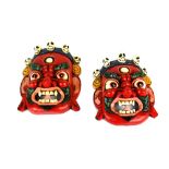 A pair of Tibetan hand painted carved wooden masks of demon guardians, L. 20cm.