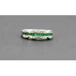 An 18ct white gold (stamped 750) ring set with step cut emeralds and diamonds, (N.5).